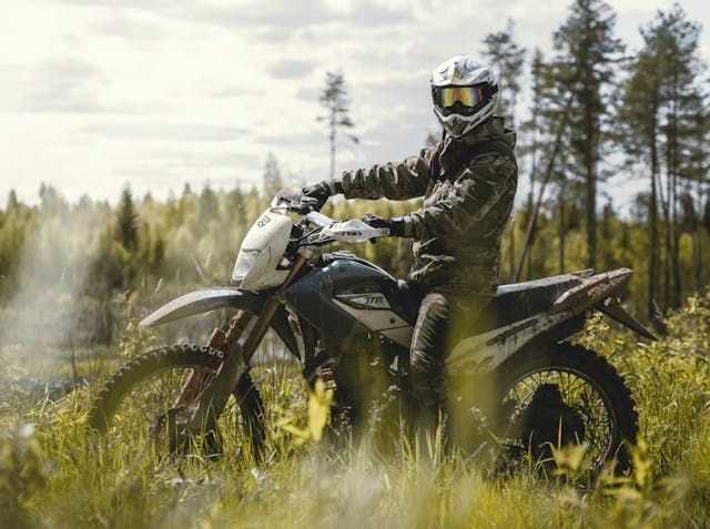 A man in a helmet and gear riding a dirt bike, complying with the Colorado motorcycle helmet law